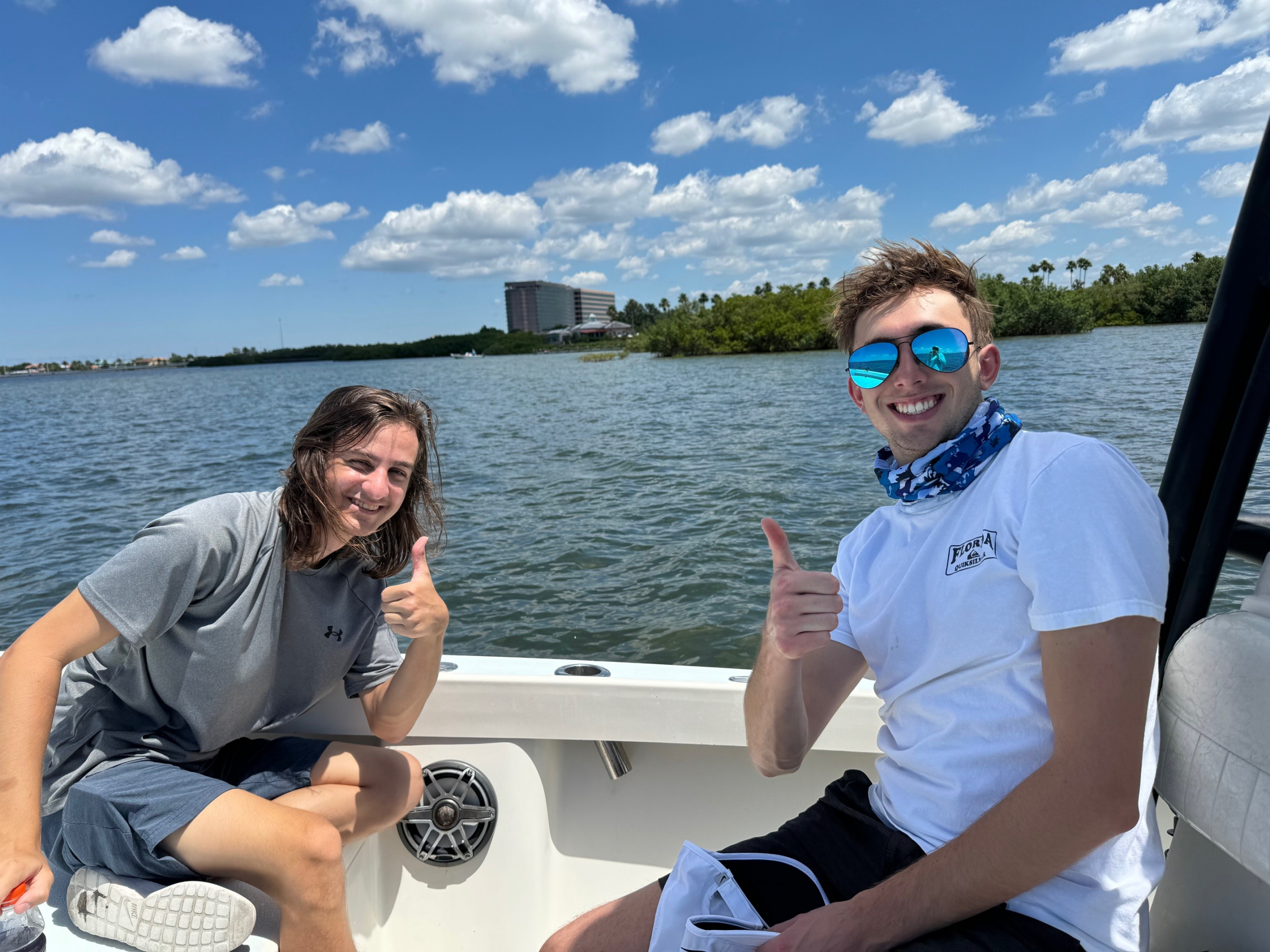 Tampa Bay Surveillance intern and staff give smiling thumbs ups from the fishing boat